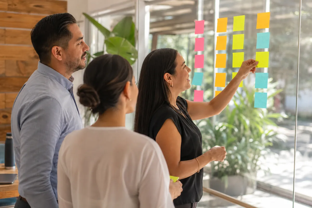Equipo de ventas moviendo notas en un tablero con columnas de embudo