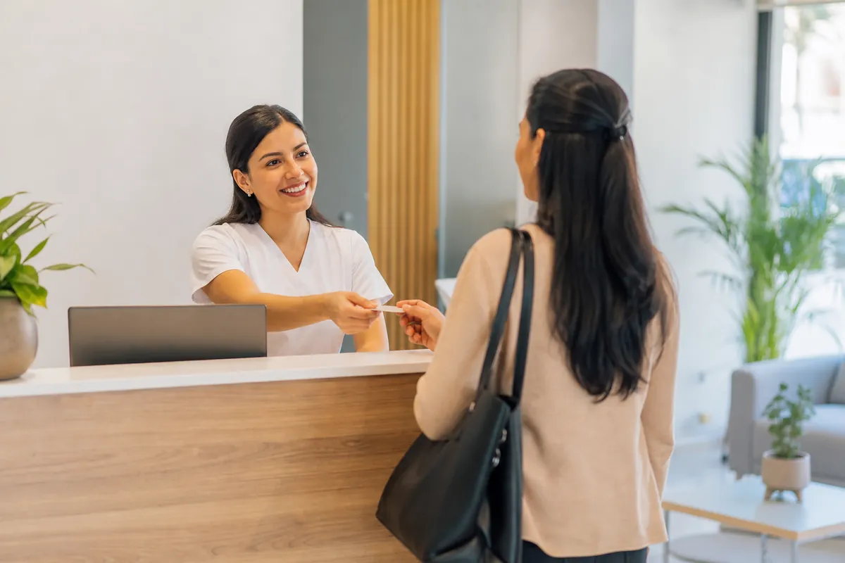 Recepcionista de una clínica dental recibiendo a una paciente